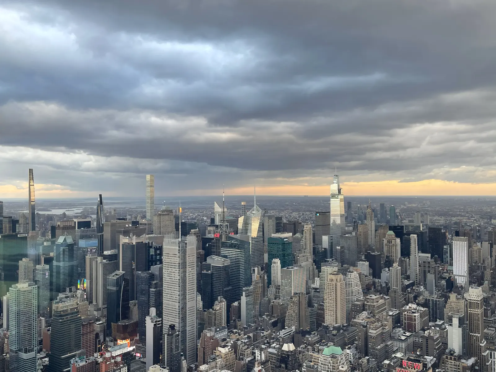 Midtown Manhattan skyline under storm clouds with a band of sunset light